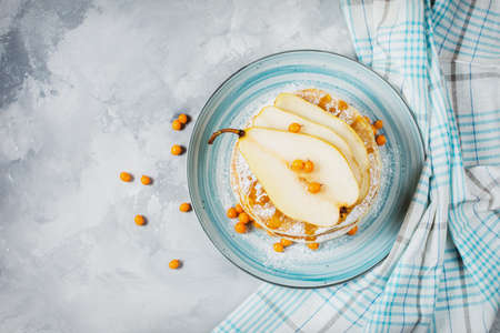 Home-made breakfast: american style pancakes served with berries, pear and honey on concrete background. Top view and copy spaceの写真素材