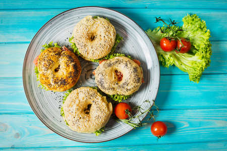 Bagels with salmon, vegetables, cream-cheese on blue wood background. Top viewの写真素材