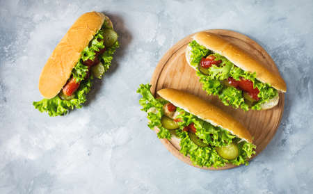 Hot dog with pickles and lettuce on concrete background. Top view.
