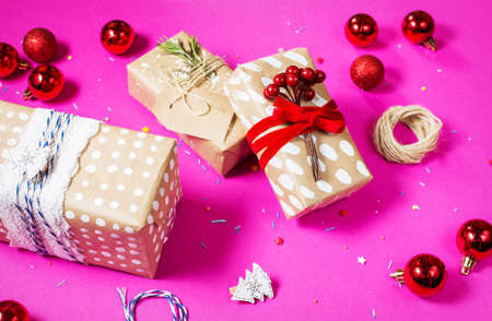 christmas decoration: red glass christmas balls and gifts on pink background