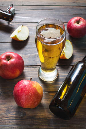 Glass of cider with apples and bottle on rustic wooden backgroundの写真素材