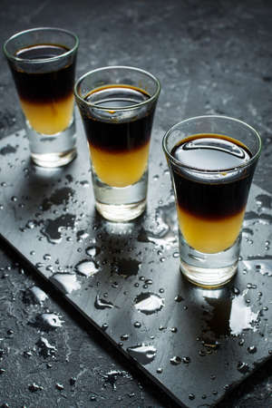 Black Shooter - Black Balsam and peach juice. Hard alcoholic shots on stone table.の写真素材