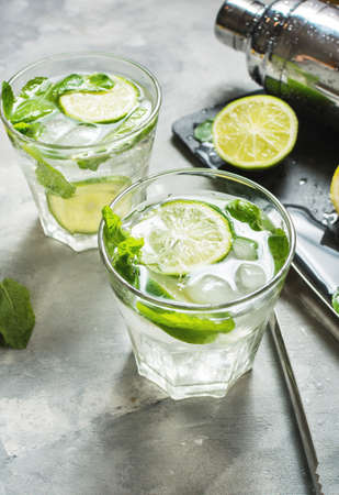 Mojito cocktail with lime and mint in highball glass on a stone table. Drink making tools and ingredients for cocktail.の写真素材