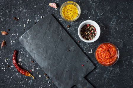 Black slate board, mustard, sauce and spices. Cooking or food background.の写真素材