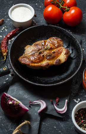 Juicy pork steak with spices on pan on dark stone background.の写真素材