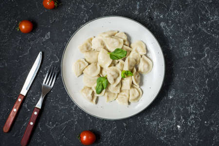Traditional russian pelmeni, ravioli, dumplings with meat on black concrete background. Top viewの写真素材