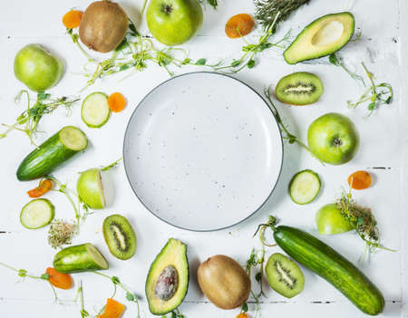 Ingredients for cooking smoothie. Organic green vegetables and fruits on wooden white rustic background. Copy space, flat lay, top view.の写真素材