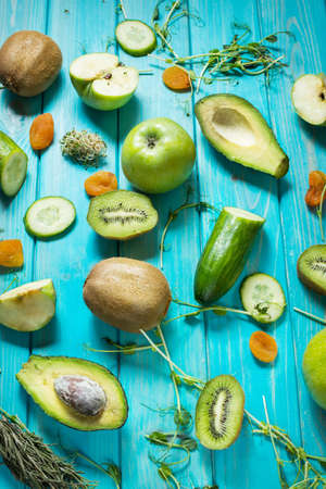 Ingredients for cooking smoothie. Organic green vegetables and fruits on blue wood backgroundの写真素材