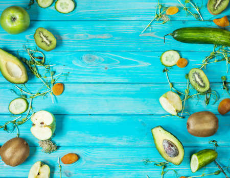 Ingredients for cooking smoothie. Organic green vegetables and fruits on wooden blue rustic background. Copy space, flat lay, top view.の写真素材
