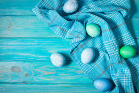 painted eggs on plate, chicken eggs, paint and brush on blue wood background, Easter decorations....