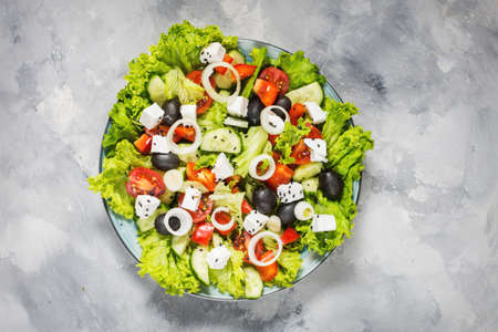 Traditional greek salad with fresh vegetables, feta cheese and olives on concrete background. Top viewの写真素材
