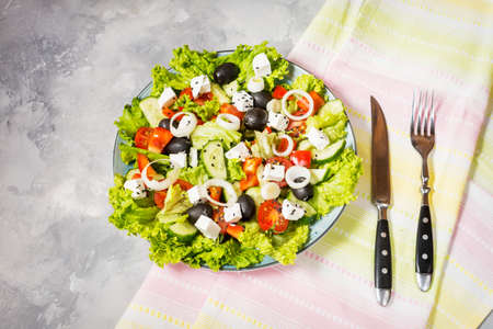 Traditional greek salad with fresh vegetables, feta cheese and olives on concrete background.の写真素材
