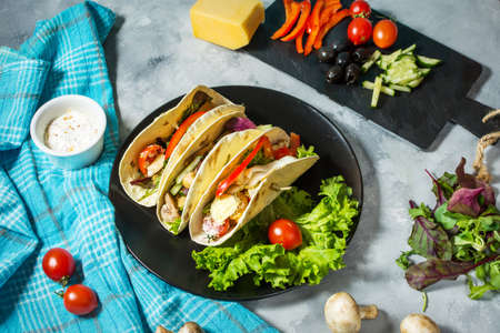 Fresh delicious mexican tacos and food ingredients on concrete rustic background.の写真素材