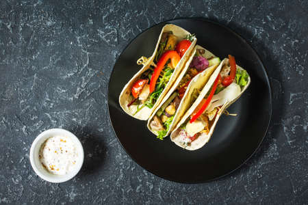 Fresh delicious mexican tacos on stone dark background
