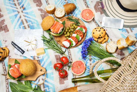Picnic setting on the grass with basket, sandwiches, fruit, strawberry, salad and olives. Top viewの写真素材