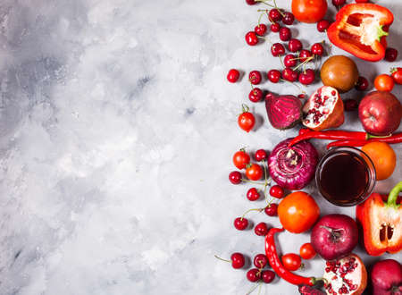 Raw red organic vegetables with fresh ingredients for healthily cooking on concrete background, top view. Vegan or diet food concept. Copy spaceの写真素材