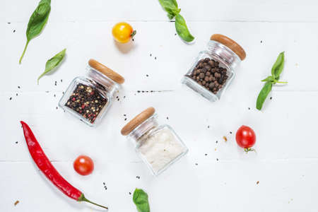 Herbs and spices in jars over on white wooden table. Ingredients for cooking. Top view