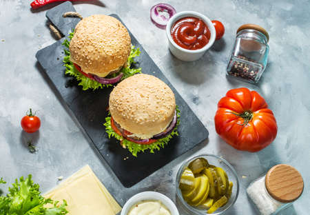 Tasty grilled homemade burgers with beef, tomato, cheese on concrete backgroundの写真素材