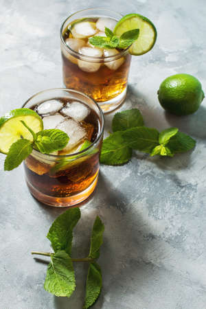 Rum and cola. Cuba Libre drink with lime and ice on rustic concrete table.の写真素材