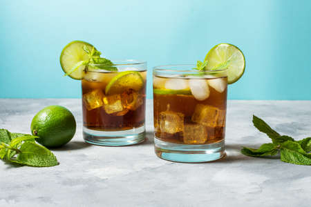 Rum and cola. Cuba Libre drink with lime and ice on rustic concrete table.の写真素材