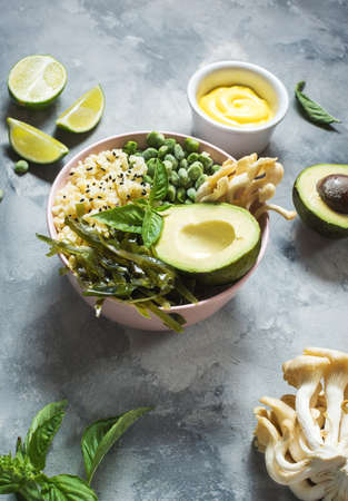 Buddha bowl recipe with quinoa, avocado, lentils, mushrooms, sea kale on concrete background.