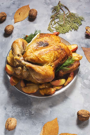 Roasted turkey with apples on a rustic concrete table decorated with walnut and autumn leaf.の写真素材