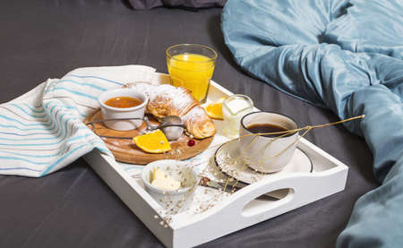 Breakfast in bed with coffee, croissants and orange juice on white tray.の写真素材