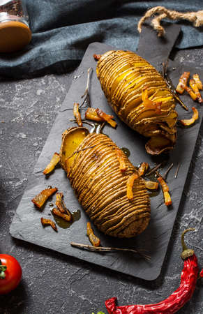 Roasted hasselback potato on dark stone backgroundの写真素材
