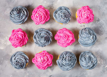 Tasty pink and grey cupcakes in a row on concrete background. Top viewの写真素材