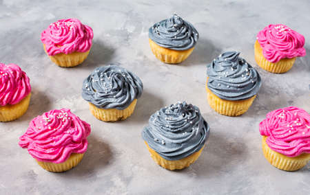 Tasty pink and grey cupcakes in a row on concrete backgroundの写真素材