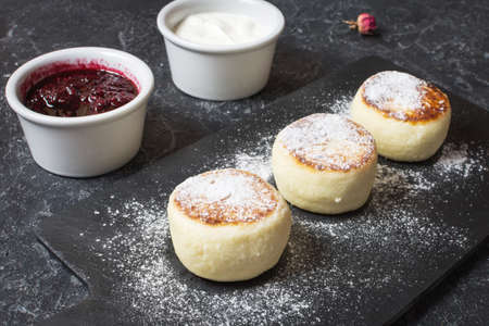 Cottage cheese pancakes on stone background. Syrniki with sour cream. Homemade food