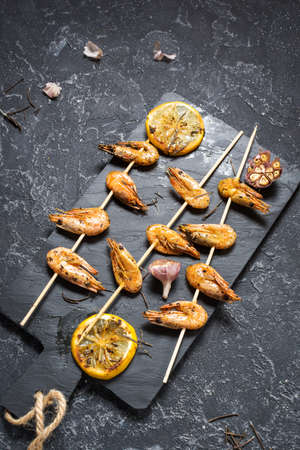 Grilled shrimp skewers with herbs, garlic and lemon on stone background. Seafood, shelfish.の写真素材