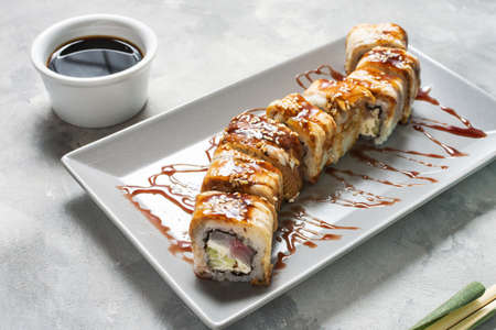 Golden dragon sushi roll with tuna, eel, cucumber served on concrete background.