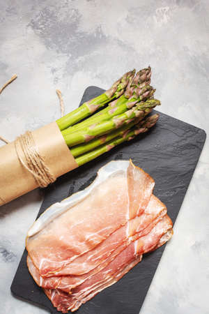 Fresh green asparagus and bacon on a rustic concrete table.の写真素材
