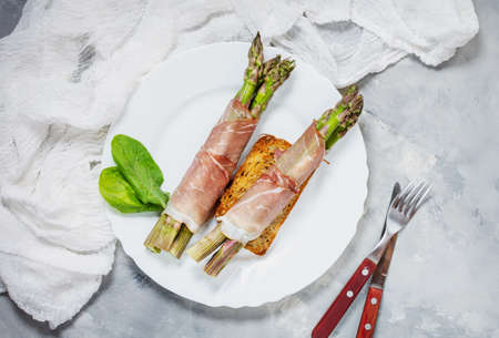 Fresh Young Asparagus Wrapped in Prosciutto Meat on a rustic concrete table. Top viewの写真素材