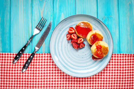 Russian syrniki or cottage cheese fritters or pancakes served with strawberry on blue wood background. Top viewの写真素材