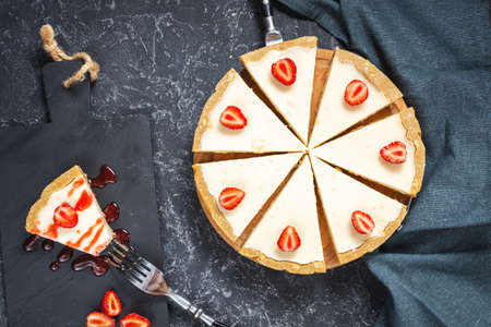 Homemade cheesecake with fresh strawberries sliced on black stone background, top viewの写真素材