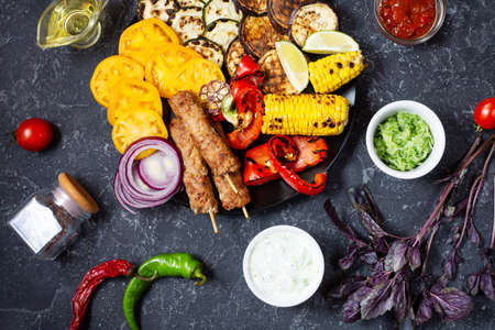 Assorted delicious grilled vegetables and meat on a dark stone background. Summer food barbecue. Top viewの写真素材
