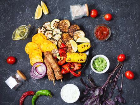 Assorted delicious grilled vegetables and meat on a dark stone background. Summer food barbecue. Top viewの写真素材