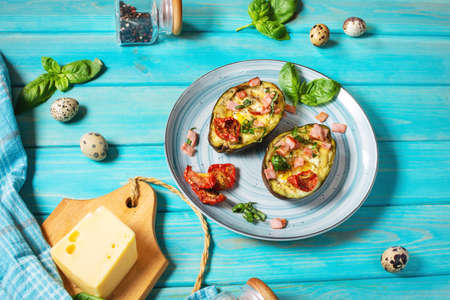 Keto diet: Avocado with ham, quail eggs, cheese on blue wooden backgroundの写真素材