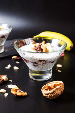 Chia pudding parfait puff with banana, yogurt and nuts on black backgroundの写真素材