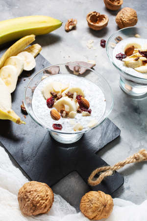 Chia pudding parfait puff with banana, yogurt and nuts on concrete backgroundの写真素材