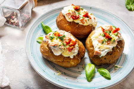 Baked stuffed potatoes with bacon, tomato and cheese on concrete background.の写真素材