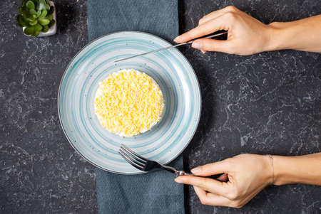 Traditional russian salad Mimosa on black stone table.