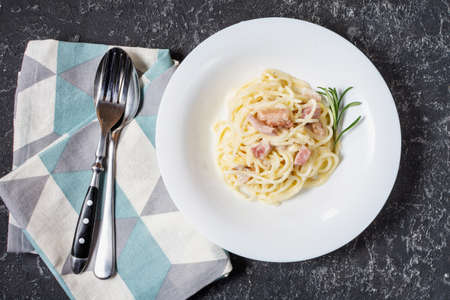 Pasta carbonara served on deep plate decorated with rosemary. Top view