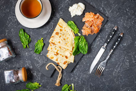Delicious breakfast or brunch - crepes with smoked salmon, spinach and sour cream on stone...