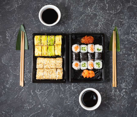 Various kinds of sushi served on black stone background.