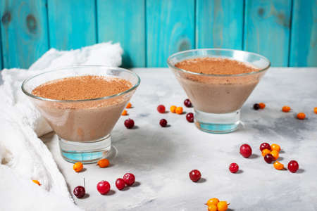 Two glasses of cheese-chocolate mousse with berries on a concrete background