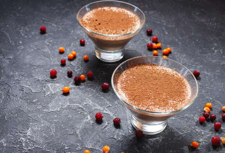 Two glasses of cheese-chocolate mousse with berries on a dark stone backgroundの写真素材