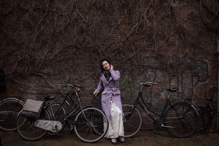 Positive woman standing by the old wall with lots of bicycles in Amsterdamの写真素材